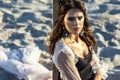 Beauty portrait of attractive brunette woman posing on sandy beach at sunset with makeup, earrings and hairstyle. looking at Royalty Free Stock Photo