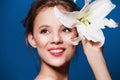 Beauty portrait of attractive, fresh woman with the lily flower on blue Royalty Free Stock Photo