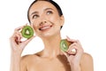 Young woman with clean radiant skin showing kiwi halves, on white background, beauty and skin care concept Royalty Free Stock Photo