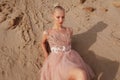 Beauty portrait of a beautiful blonde woman posing in embroidery dress on desert, lying on golden sand with closed eyes. Royalty Free Stock Photo