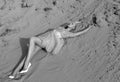 Beauty portrait. Beautiful blonde woman posing in embroidery dress on desert, lying on sand. Black and white photo Royalty Free Stock Photo
