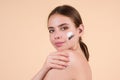 Beauty portrait of a beautiful half naked woman applying face cream isolated on studio background. Skin care product Royalty Free Stock Photo