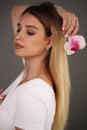 Beauty Portrait. Beautiful Stylish Girl with Orchid Flower. Perfect Face Skin. Healthy hair. Royalty Free Stock Photo