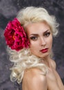 Beauty portrait of a blonde with a big red flower in her hair