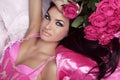 Beauty portrait of brunette girl with pink Roses lying on the be Royalty Free Stock Photo