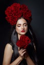 Beauty portrait brunette woman with crown of roses flowers on her head. Bright red makeup and lipstick. Rose flowers in the hands Royalty Free Stock Photo