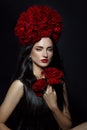 Beauty portrait brunette woman with crown of roses flowers on her head. Bright red makeup and lipstick. Rose flowers in the hands Royalty Free Stock Photo