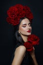 Beauty portrait brunette woman with crown of roses flowers on her head. Bright red makeup and lipstick. Rose flowers in the hands Royalty Free Stock Photo