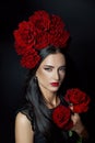 Beauty portrait brunette woman with crown of roses flowers on her head. Bright red makeup and lipstick. Rose flowers in the hands Royalty Free Stock Photo
