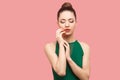 Beauty portrait of calm serious beautiful young woman with bun hairstyle and makeup in green dress standing, with closed her eyes Royalty Free Stock Photo