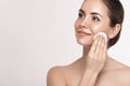 Beauty portrait of a cheerful young topless woman removing face make-up with a cotton pad.