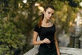 Frontal portrait of a girl with ponytail hair, dressed in black dress, looks at the camera, being on the balcony. Royalty Free Stock Photo