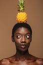 Beauty portrait of half-naked african woman holding pineapple on her head Royalty Free Stock Photo
