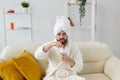 Beauty portrait of handsome beautiful guy in towel and bathrobe holding tube of body cream lotion in hand. Spa, body and