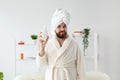 Beauty portrait of handsome beautiful guy in towel and bathrobe holding tube of body cream lotion in hand. Spa, body and