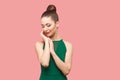 Beauty portrait of happy beautiful young woman with bun hairstyle and makeup in green dress standing with closed eyes, touching Royalty Free Stock Photo