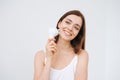 Beauty portrait of happy smiling woman with dark long hair with facial massager in hand on clean fresh skin face on the white