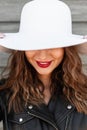 Beauty portrait happy woman with clean skin with sexy red lips and cute smile with curly brown hair in fashion black jacket in hat Royalty Free Stock Photo