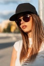Beauty portrait hipster young girl with sexy lips in white torn top in fashion sunglasses in stylish cool baseball cap on sun Royalty Free Stock Photo