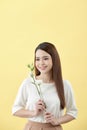 Beauty portrait of lady 20s holding white lisianthus flowers over yellow background Royalty Free Stock Photo