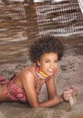 Beauty portrait of natural girl with afro lying on sand