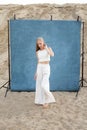 Beauty portrait outdoors on sand in front of blue backdrop, pretty female posing Royalty Free Stock Photo