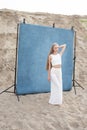 Beauty portrait outdoors on sand in front of blue backdrop, pretty female posing Royalty Free Stock Photo