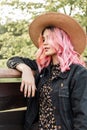 Beauty portrait pretty stylish young woman with pink hair in vintage straw hat in stylish casual youth denim jacket near wooden Royalty Free Stock Photo