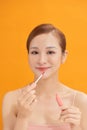 Beauty portrait of a pretty young topless woman wearing makeup isolated over yellow background, applying lip gloss Royalty Free Stock Photo