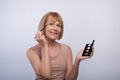 Beauty portrait of senior woman applying eye shadow with cosmetic brush, using swatches palette on light background Royalty Free Stock Photo