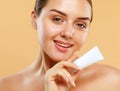 Beauty portrait of a smiling beautiful young woman holding tube with a face cream Royalty Free Stock Photo