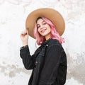 Beauty portrait smiling stylish young woman in fashion vintage straw hat in denim fashionable jacket near building on street. Cute Royalty Free Stock Photo