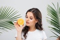 Beauty portrait of a smiling woman with brunette hair posing with green leaves and holding sliced orange isolated over white backg Royalty Free Stock Photo