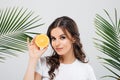 Beauty portrait of a smiling woman with brunette hair posing with green leaves and holding sliced orange isolated over white backg Royalty Free Stock Photo