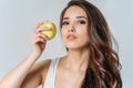 Beauty portrait of smiling young asian woman girl holding green apple near clean face on grey background Royalty Free Stock Photo