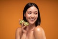 Beauty portrait of smiling young woman with natural freckles. Girl holding organic kiwi in hand. Skin care concept Royalty Free Stock Photo
