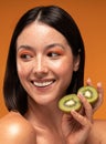 Beauty portrait of smiling young woman with natural freckles. Girl holding organic kiwi in hand. Skin care concept Royalty Free Stock Photo