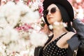 Beauty portrait stylish beautiful young woman in fashion sunglasses in elegant hat in fashionable spring black clothes in park Royalty Free Stock Photo