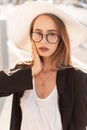 Beauty portrait stylish young woman in trendy glasses in fashionable black jacket in white t-shirt in straw hat outdoors. Lovely Royalty Free Stock Photo