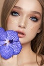 Beauty portrait of a woman with a blue Vanda Orchid in her hand. Natural cosmetics made of flower petals, clean delicate skin of Royalty Free Stock Photo