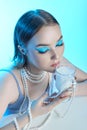 Beauty portrait woman makeup blue arrows eyes, beads jewelry around her neck, blue dress, woman at table with milk. Art makeup Royalty Free Stock Photo