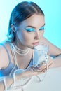 Beauty portrait woman makeup blue arrows eyes, beads jewelry around her neck, blue dress, woman at table with milk. Art makeup Royalty Free Stock Photo