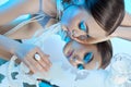 Beauty portrait woman makeup blue arrows eyes, beads jewelry around her neck, blue dress, woman at table with milk. Art makeup Royalty Free Stock Photo