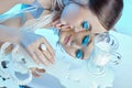 Beauty portrait woman makeup blue arrows eyes, beads jewelry around her neck, blue dress, woman at table with milk. Art makeup Royalty Free Stock Photo