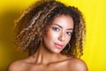 Beauty portrait of young african american girl with afro hairstyle. Girl posing on yellow background, looking at camera. Royalty Free Stock Photo