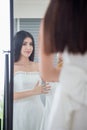 Beauty portrait of young asian bride  is looking into the mirror and smiling while choosing wedding dress in  wedding salon of Royalty Free Stock Photo