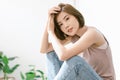 Beauty portrait of young Asian woman with perfect fresh clean skin resting at home while sitting on table and looking at camera. Royalty Free Stock Photo