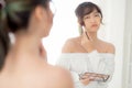 Beauty portrait young asian woman smiling with face looking mirror applying makeup with brush cheek in the bedroom.