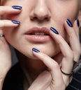 Beauty portrait of young female with blue manicure on dark background