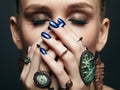 Young woman with eyes closed and many bijouterie rings with stones on fingers